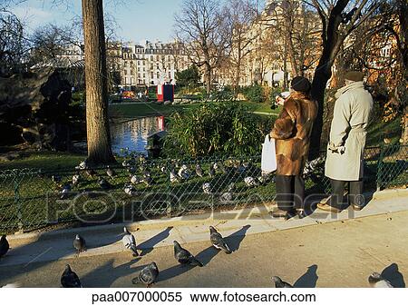 Stock Photography - France, Paris, couple and pigeons in park. Fotosearch
