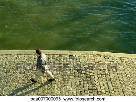 France, Paris, man walking along quay of River Seine View Large Photo Image Stock Photography - France, Paris, man walking along quay of River Seine. Fotosearch