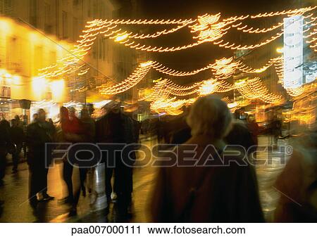 Stock Image - France, Paris, people in street at night, blurred. Fotosearch