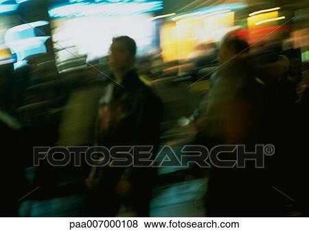 Stock Photo - France, Paris, people in street at night, blurred. Fotosearch