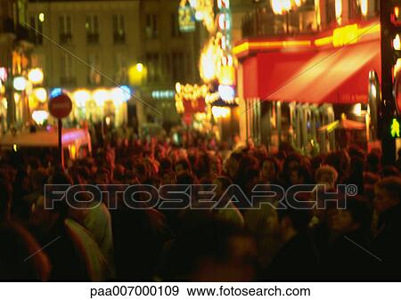 Stock Photo - France, Paris, people in street at night, blurred . Fotosearch