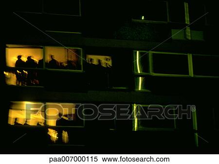 Stock Photography - France, Paris, people silhouetted in apartment building at night. Fotosearch