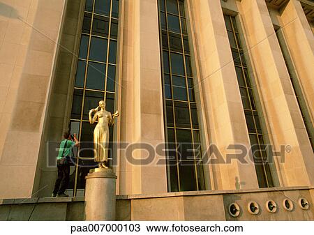 Stock Image - France, Paris, person photographing statue in front of Chaillot Palace. Fotosearch