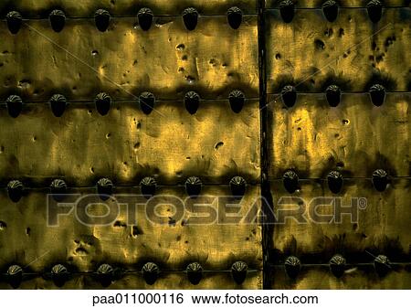 Stock Photograph - Brass door with studs, close-up. Fotosearch