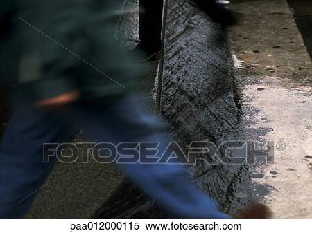 People stepping over water running in street gutter View Large Photo Image Stock Photography - People stepping over water running in street gutter. Fotosearch