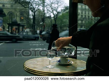Person sitting at table on cafe terrace, pouring water from carafe View Large Photo Image Stock Photograph - Person sitting at table on cafe terrace, pouring water from carafe. Fotosearch