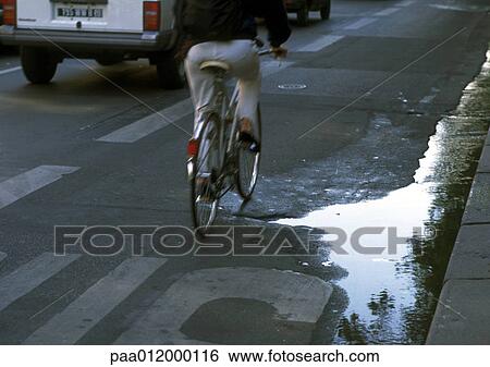 Stock Photograph - Puddle of water on street with traffic. Fotosearch