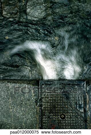 Stock Photography - Water pouring into gutter, high angle view, close-up. Fotosearch