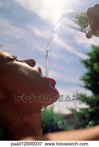 Woman pouring water into mouth under sun View Large Photo Image Stock Photo - Woman pouring water into mouth under sun. Fotosearch