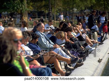 Stock Photo - Crowd sitting near edge of fountain in park, blurred.. Fotosearch