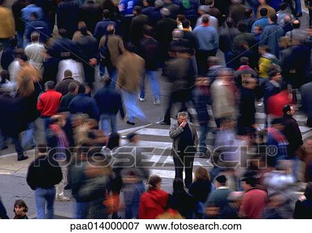Stock Photo - Crowd walking by man standing in opposite direction, blurred motion. Fotosearch
