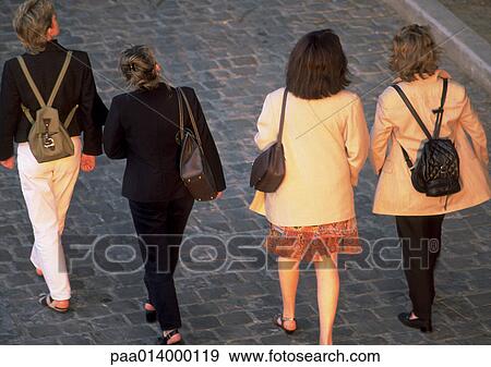 Stock Photo - Four ladies walking on cobblestones, high angle, rear view.. Fotosearch