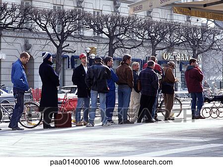 Stock Photograph - Group of people dressed for cold weather waiting in line on sidewalk.. Fotosearch
