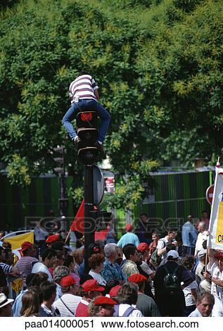 Man sitting on traffic light post in middle of crowd. View Large Photo Image Stock Image - Man sitting on traffic light post in middle of crowd.. Fotosearch