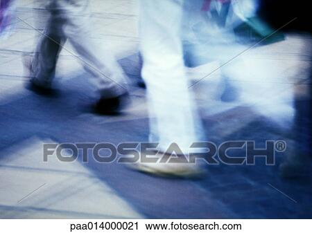 Stock Image - People walking on sidewalk, blurred motion. Fotosearch