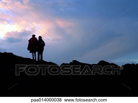 Two people standing on rocky mountain, silhouette. View Large Photo Image Stock Photo - Two people standing on rocky mountain, silhouette.. Fotosearch