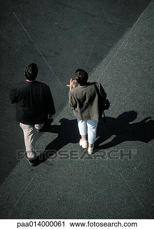Stock Image - Two people walking on asphalt, high angle view. Fotosearch