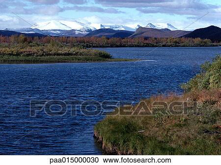 Stock Image - Finland, lake with snow covered mountains in background. Fotosearch