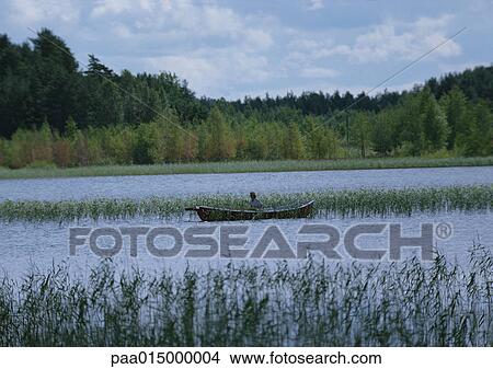 Picture - Finland, man in boat in marshy landscape. Fotosearch