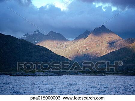 Stock Image - Norway, mountains with shadows next to sea. Fotosearch