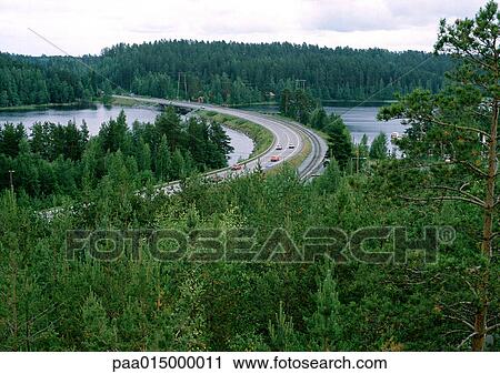 Stock Image - Sweden, road crossing river in forest. Fotosearch