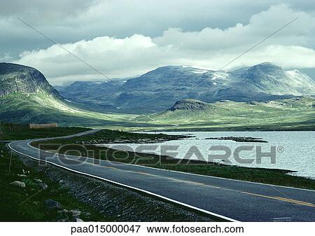 Stock Photo - Sweden, road next to sea and mountains. Fotosearch