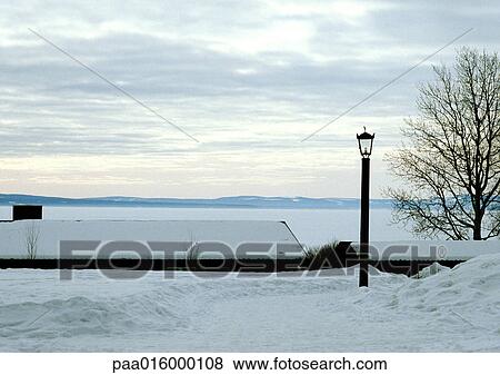 Stock Photo - Finland, snow-covered houses near water's edge. Fotosearch