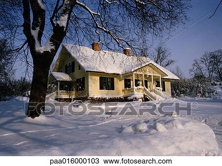 Stock Image - Sweden, snow-covered house in rural setting in daylight, snow covering ground. Fotosearch