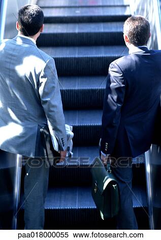 Businessmen riding escalator, rear view. View Large Photo Image Stock Photography - Businessmen riding escalator, rear view.. Fotosearch