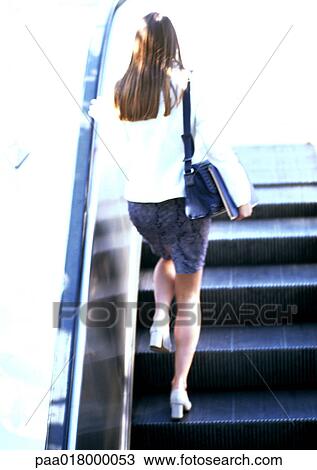 Businesswoman walking up escalator, rear view. View Large Photo Image Stock Image - Businesswoman walking up escalator, rear view.. Fotosearch
