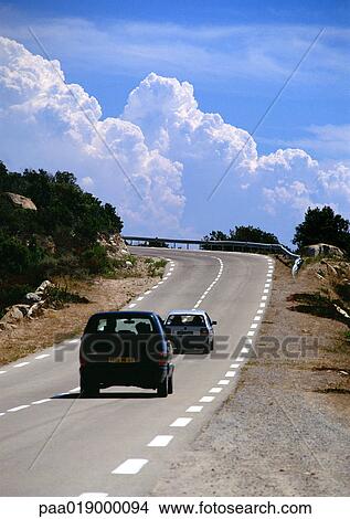 Cars on rural road, cloudscape in background View Large Photo Image Picture - Cars on rural road, cloudscape in background. Fotosearch
