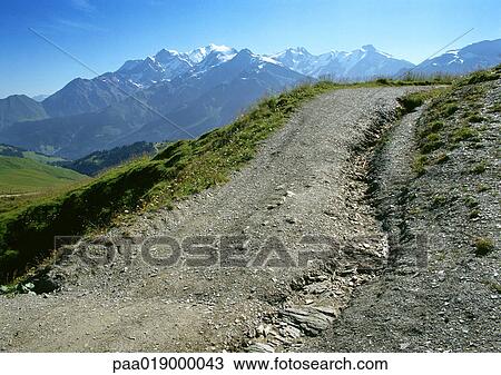 France, Alpes, dirt uphill road with snow-covered mountains in background View Large Photo Image Stock Image - France, Alpes, dirt uphill road with snow-covered mountains in background. Fotosearch