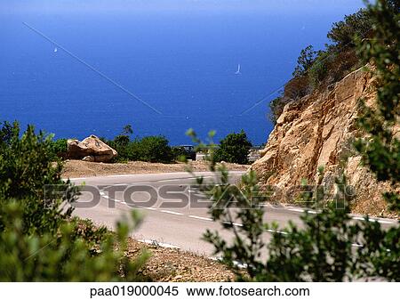 France, Corsica, road curving around mountain, sea in background. View Large Photo Image Stock Photography - France, Corsica, road curving around mountain, sea in background.. Fotosearch