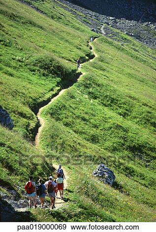 France, Savoie, hikers walking on footpath through green hillside View Large Photo Image Stock Photo - France, Savoie, hikers walking on footpath through green hillside. Fotosearch