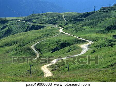 Stock Image - France, Savoie, road winding through hilly area.. Fotosearch