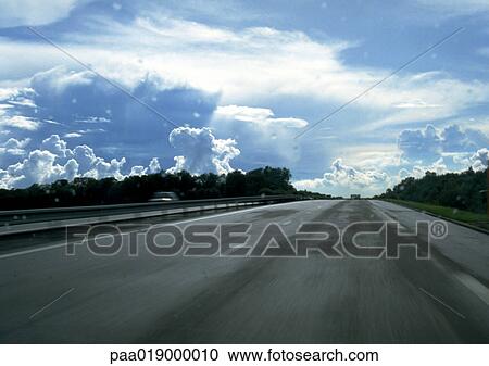 Stock Image - Straight road, cloudy sky.. Fotosearch