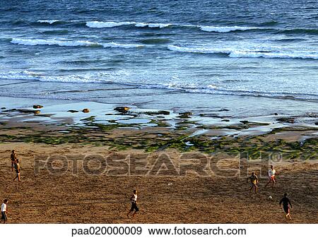 Stock Photo - Children playing soccer on seaside. Fotosearch