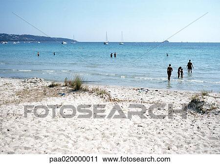 Stock Image - Corsica, people wading at beach. Fotosearch