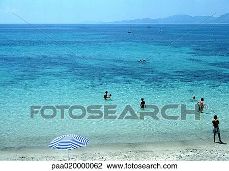 Stock Image - Corsica, people wading at beach. Fotosearch