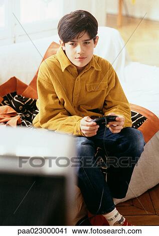 Boy playing video games on couch. View Large Photo Image Stock Image - Boy playing video games on couch.. Fotosearch