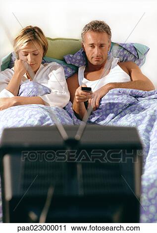 Couple lying in bed watching television. View Large Photo Image Stock Image - Couple lying in bed watching television.. Fotosearch