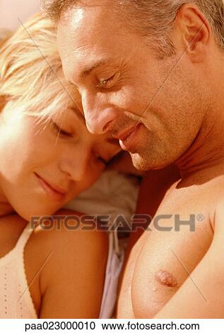 Stock Image - Couple lying together, warm toned.. Fotosearch