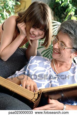 Girl looking over senior's shoulder at book. View Large Photo Image Stock Image - Girl looking over senior's shoulder at book.. Fotosearch