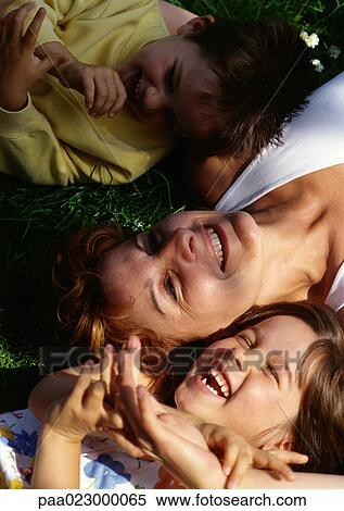 Stock Photography - Mother laying on grass with children, view from above.. Fotosearch