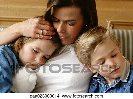 Woman between two children, holding little girl's head to her chest, little boy leaning against her, close-up View Large Photo Image Picture - Woman between two children, holding little girl's head to her chest, little boy leaning against her, close-up. Fotosearch