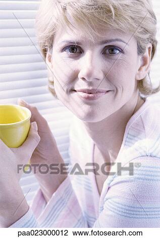 Woman facing camera holding a cup in both hands, portrait. View Large Photo Image Stock Image - Woman facing camera holding a cup in both hands, portrait.. Fotosearch