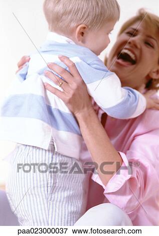 Stock Photo - Woman holding boy in hands, laughing.. Fotosearch