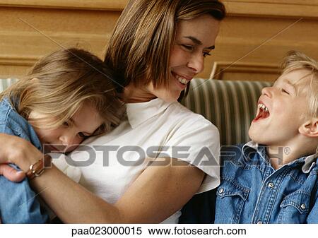 Woman holding girl in arms, looking at boy laughing View Large Photo Image Stock Photography - Woman holding girl in arms, looking at boy laughing. Fotosearch