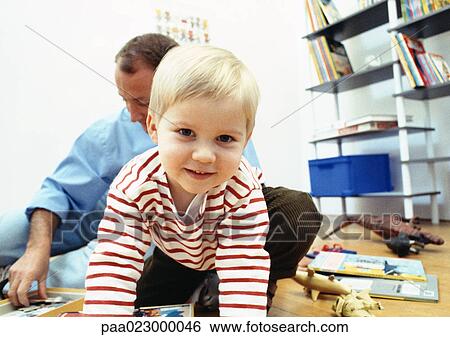 Young child facing camera in room with father View Large Photo Image Stock Photograph - Young child facing camera in room with father. Fotosearch