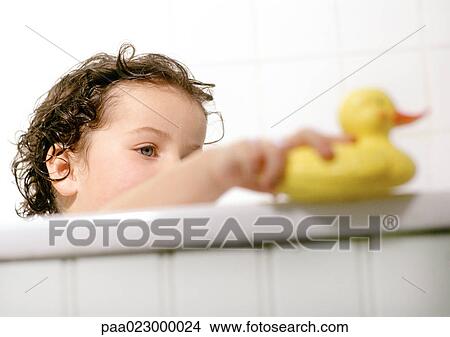Picture - Young child playing with rubber duck in bath tub.. Fotosearch
